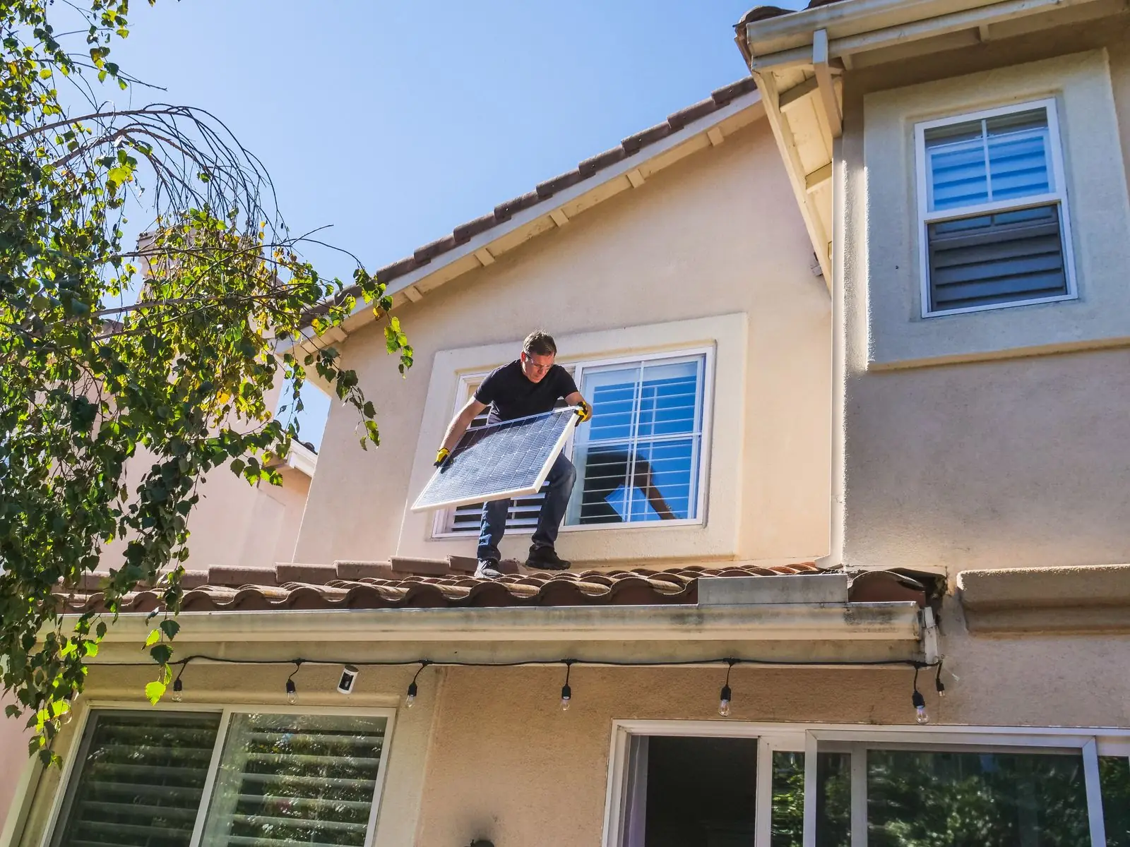Profissional em pé no telhado segurando painel solar