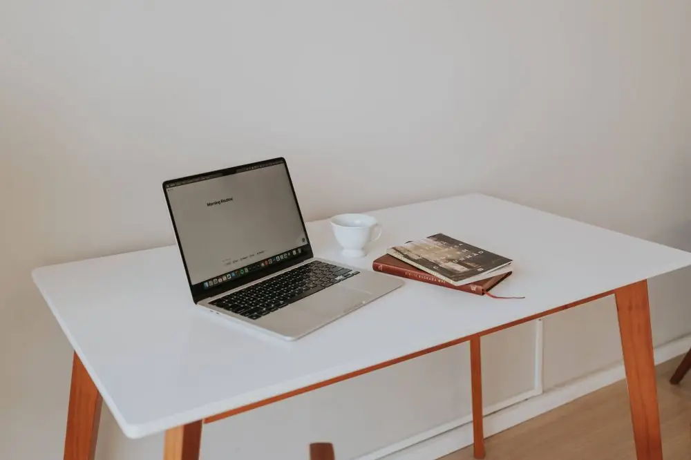 Mesa de escritório planejada com notebook, caderno e xícara