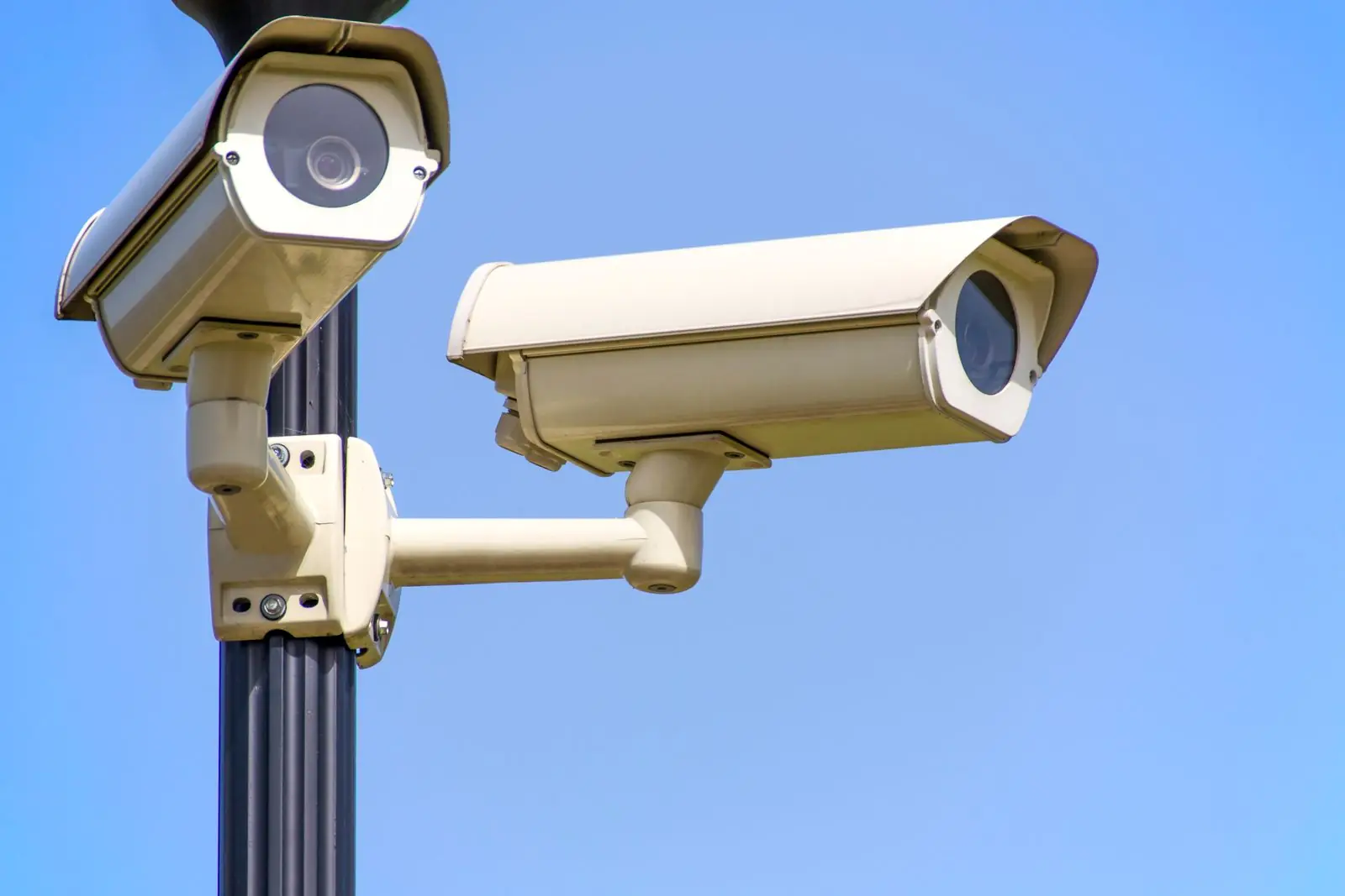 Câmera CCTV branca montada em poste sob céu azul
