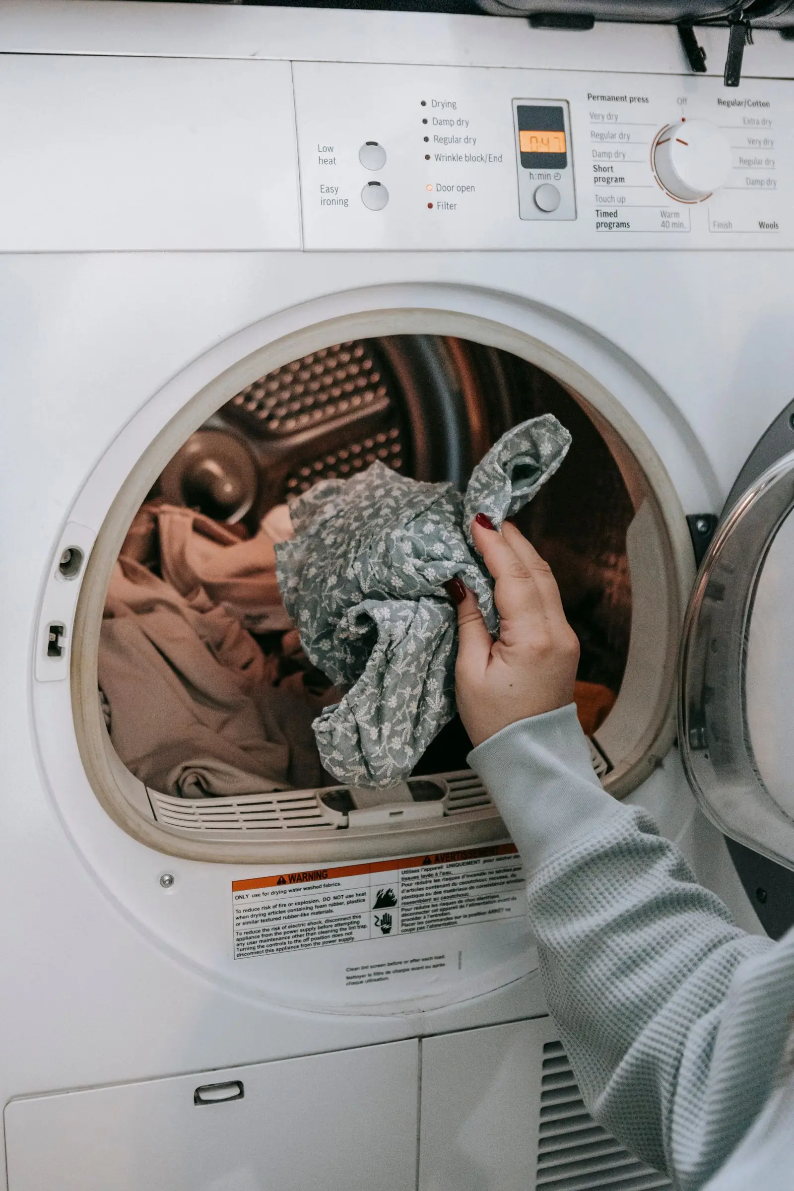 Pessoa colocando roupas na máquina de lavar